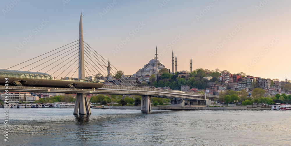 Fototapeta premium Golden Horn Metro Bridge (Halic Bridge) overlapping Suleymaniye Mosque before sunset, Istanbul, Turkey