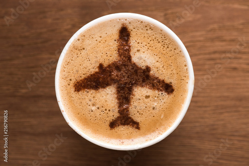 top view of cup of coffee with plane sign on wooden tabletop, traveling concept