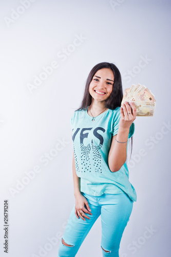 Portrait of an attractive girl in blue or turquoise t-shirt and trousers posing with a lot of money in her hand.