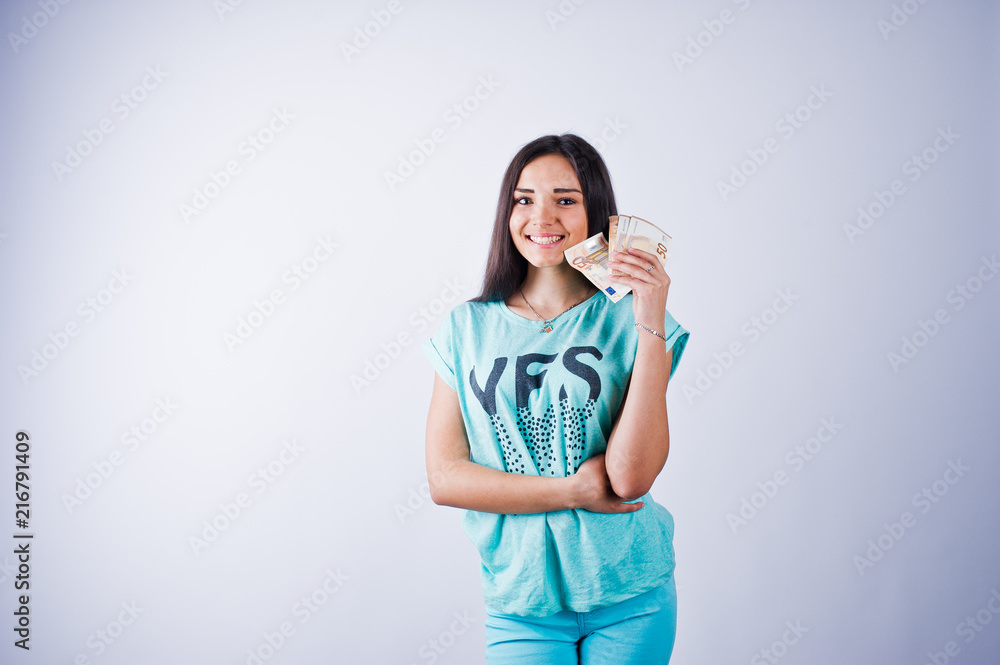 Portrait of an attractive girl in blue or turquoise t-shirt and trousers posing with a lot of money in her hand. Portrait of an attractive girl in blue or turquoise t-shirt and trousers posing with a lot of money in her hand.