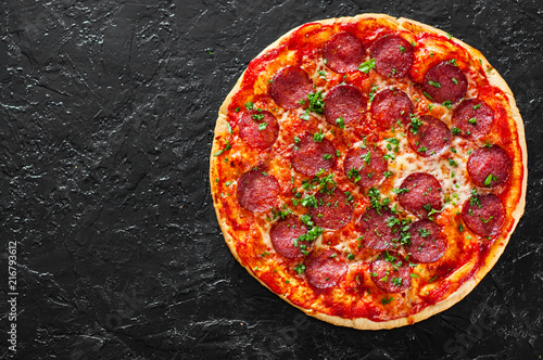 Pepperoni Pizza with Mozzarella cheese, salami, Tomatoes, pepper, Spices and Fresh Basil. Italian pizza on black background. with copy space. top view