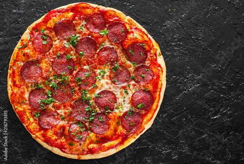 Pepperoni Pizza with Mozzarella cheese, salami, Tomatoes, pepper, Spices and Fresh Basil. Italian pizza on black background. with copy space. top view