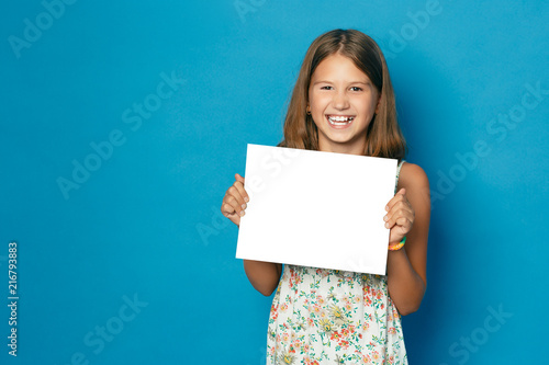 beautiful smiling child (girl) with white teeth holding in hands white blank copy space for the announcement photo
