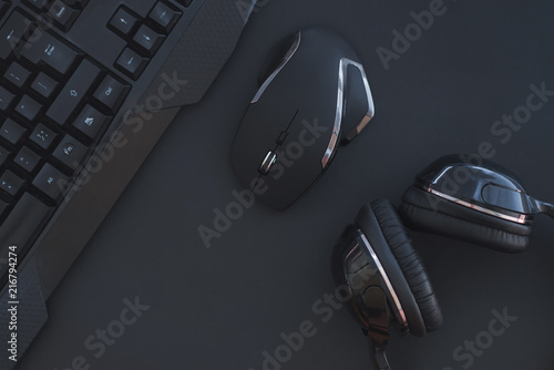 Fotografie Black mouse, the keyboard, the headphones are isolated on a dark background, the top view