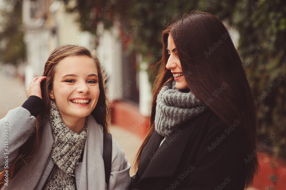 two young happy girlfriends walking on city streets in casual fashion outfits, wearing warm coats and having fun two young happy girlfriends walking on city streets in casual fashion outfits, wearing warm coats and having fun