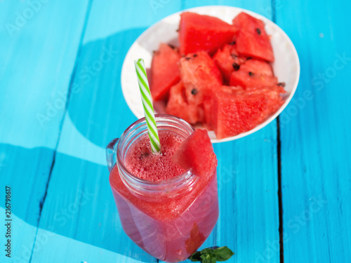 Lemonade in a glass jar with slices of lemon and mint on a wooden table