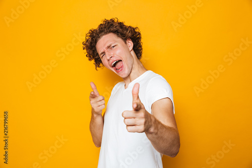 Portrait of a cheerful curly haired man pointing at camera
