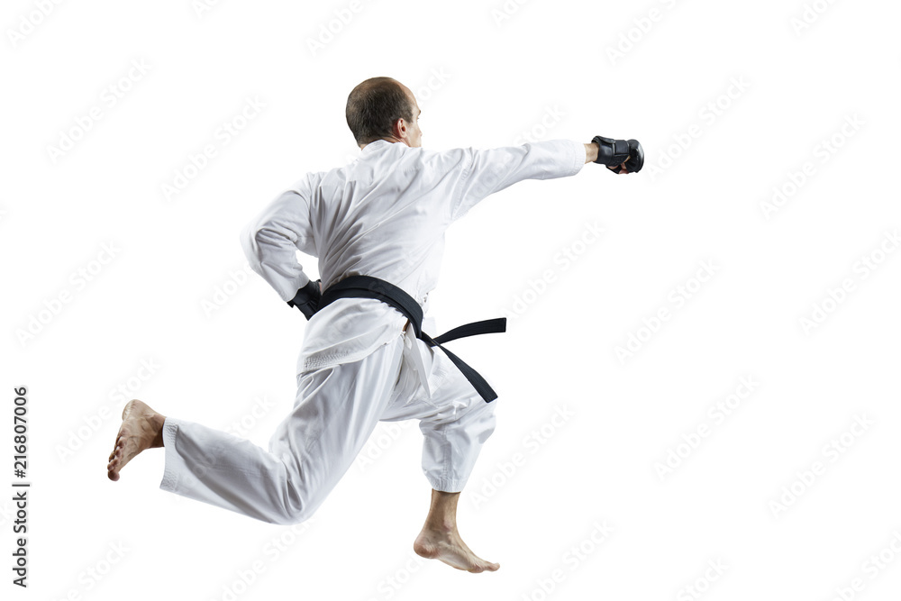 In white karategi and black gloves, the athlete beats with a hand in the jump isolated