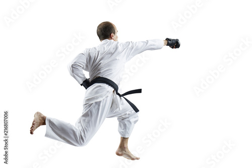 In white karategi and black gloves, the athlete beats with a hand in the jump isolated