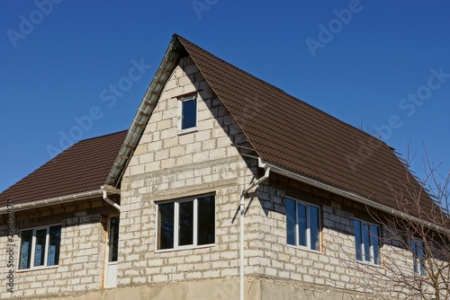 white brick house with a brown roof on the sky background © butus