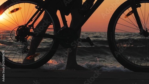 silhouette of young male with bicycle on morning beach during sunrise