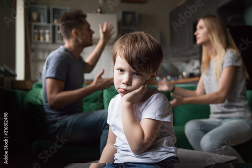 Portrait of sad son bored or tired of parents fighting, frustrated little boy upset of mom dad shouting, preschool child looking at camera feeling lack of attention, family arguments and kid concept