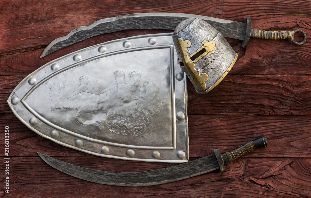 Medieval shield and sword on a wooden background