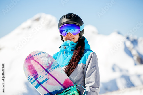 Photo of young woman tourist helmet with snowboard on snow mountains background