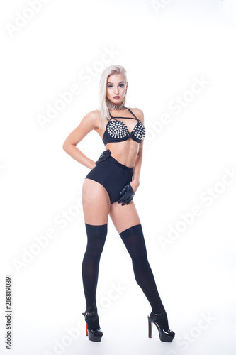Blonde in black shorts and top in rhinestones, heels in black leggings with gloves of black color on hands isolated on white background