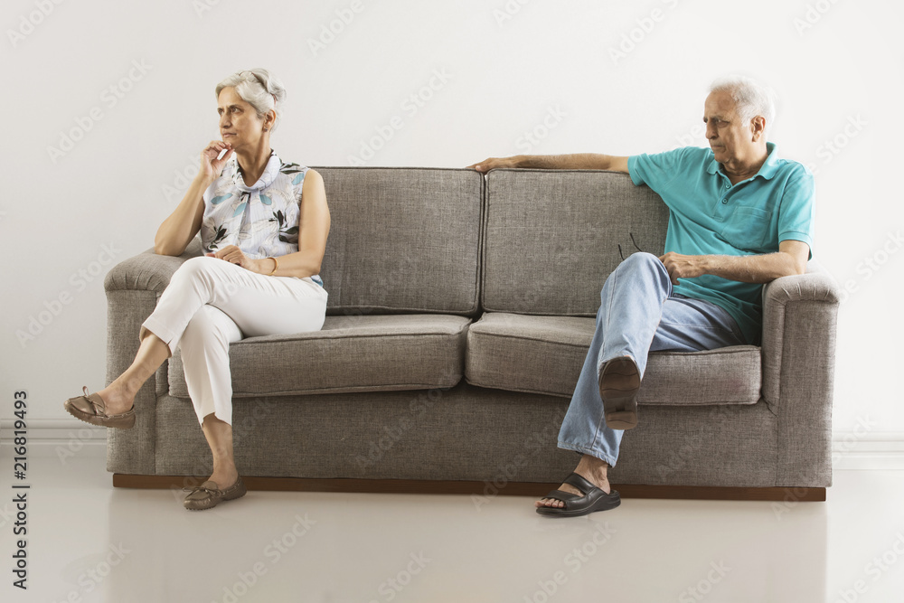 Angry senior couple sitting apart on sofa Angry senior couple sitting apart on sofa