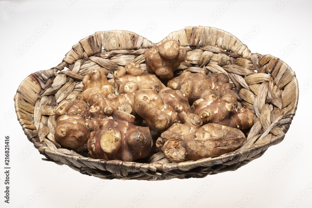 Fototapeta premium Jersalem Artichoke (Helianthus tuberosus) vegetable in wicker basket isolated on a white studio background.