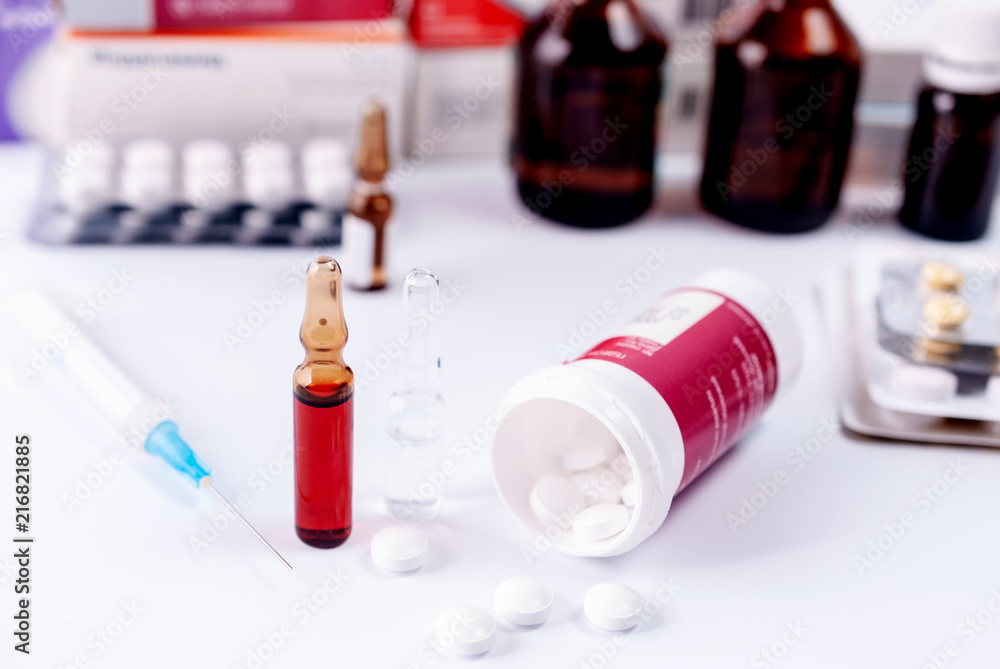 Ampoules for injection, packing of tablets and medical bottles on a white table Ampoules for injection, packing of tablets and medical bottles on a white table