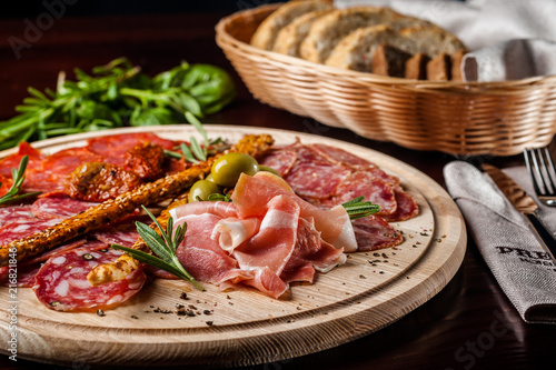 meat sliced proshto, salami, olives and pepper paprika on a wooden plate