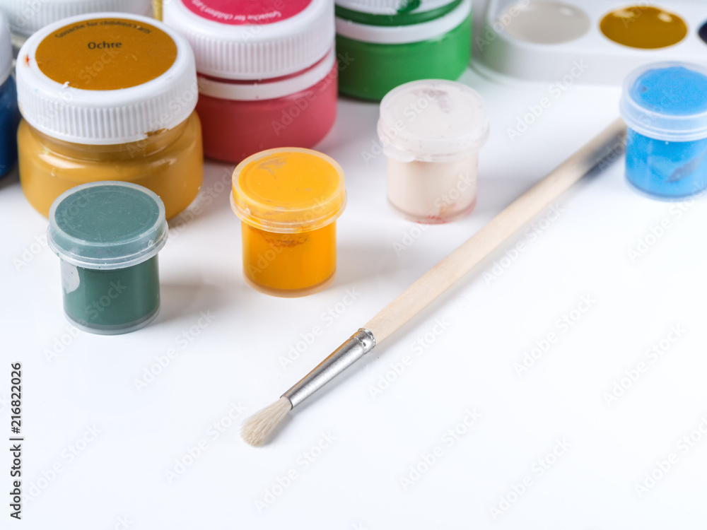 Jars with paint for drawing and brush on a white background Jars with paint for drawing and brush on a white background