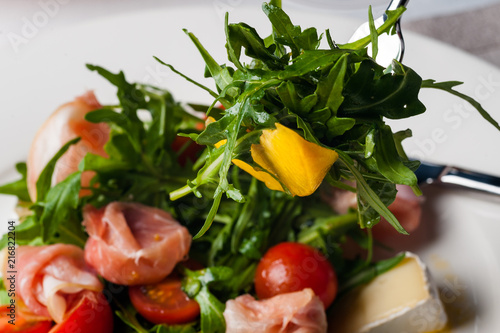 dish in the restaurant fresh salad with basil, prosciutto, tomato and mozzarella