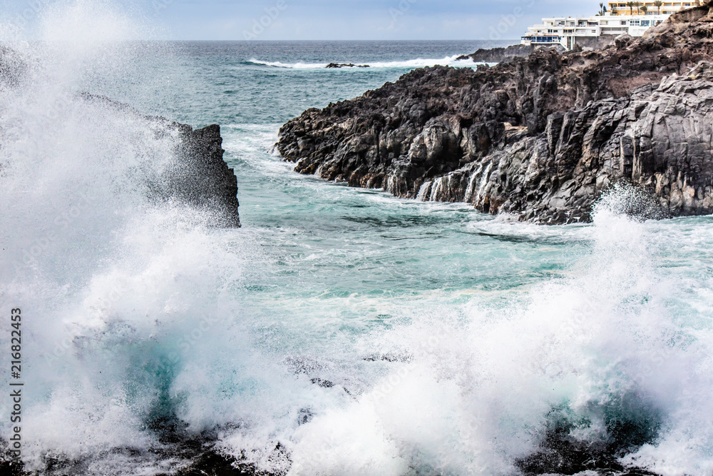 Seascape with black volcanic rocks, waves and splashes