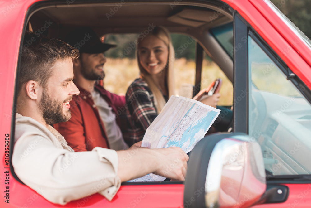 happy young travelling friends navigating while sitting in car happy young travelling friends navigating while sitting in car