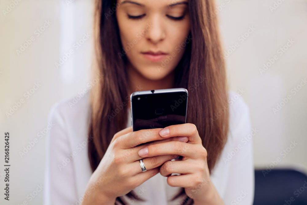 Businesswoman in her office with smartphone texting Businesswoman in her office with smartphone texting