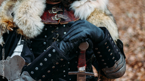 Medieval knight with sword in armor as style Game of Thrones in the forest.holds the sword