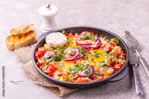 Shakshuka with toasts. Fried eggs with tomatoes, vegetables and herbs