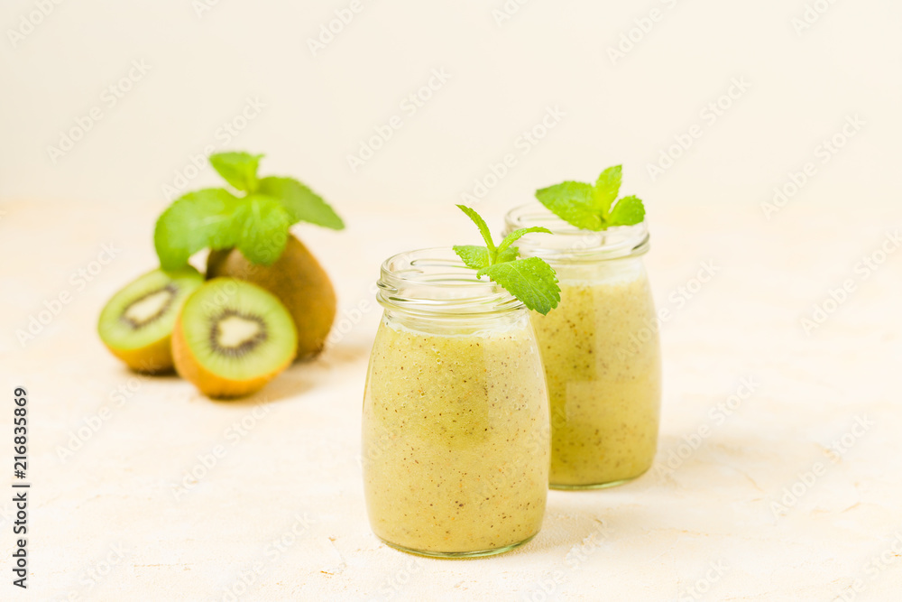 Kiwi smoothie decorated with fresh green mint leaves and raw ripe cut fruit on yellow pastel background. Kiwi smoothie decorated with fresh green mint leaves and raw ripe cut fruit on yellow pastel background.