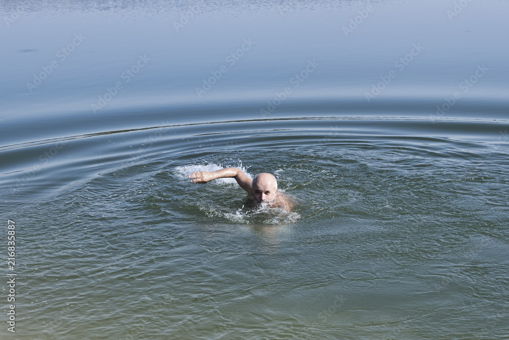 A man of mature age with a beard swims