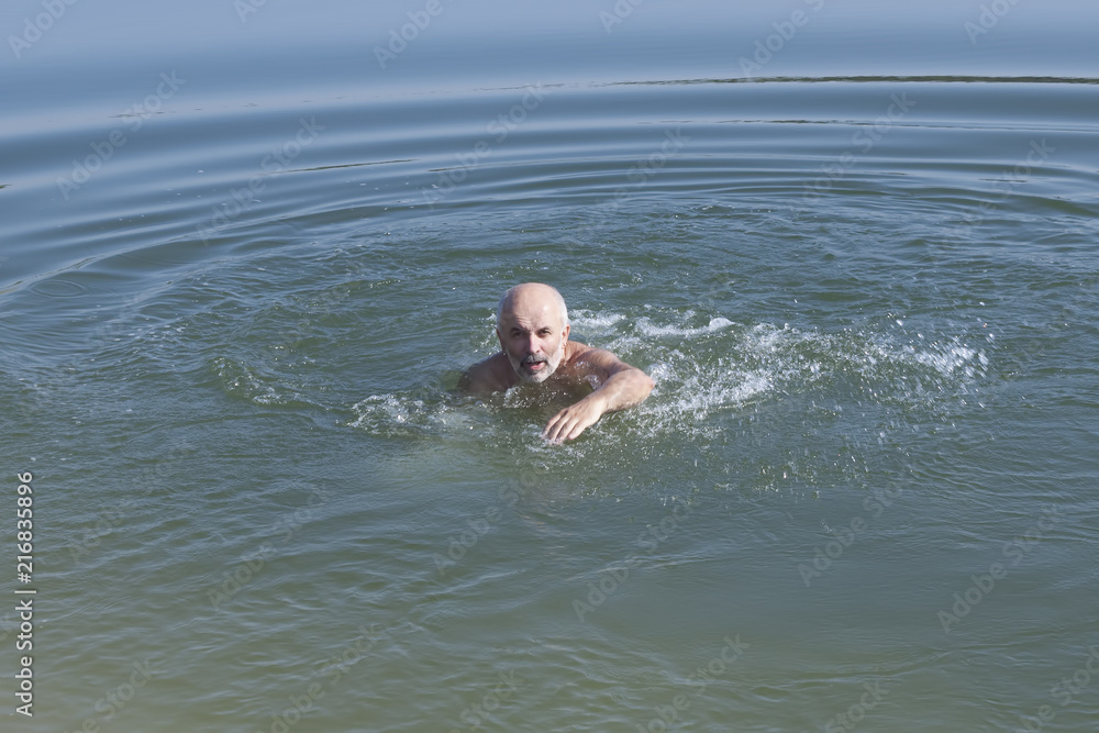 A man of mature age with a beard swims