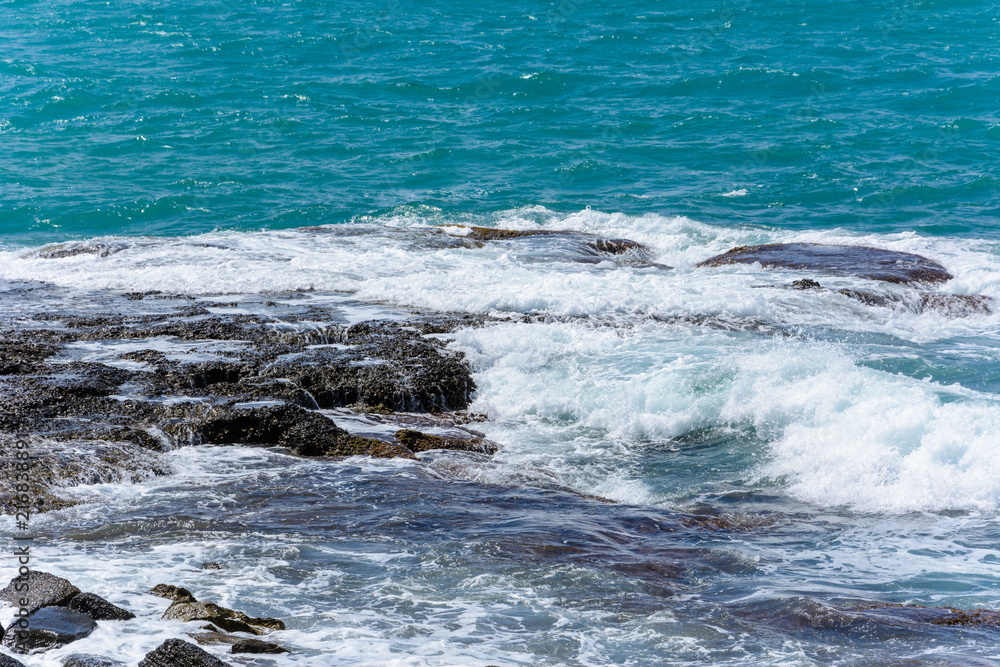 Fototapeta premium the waves of the turquoise sea break into foam on the shore stones