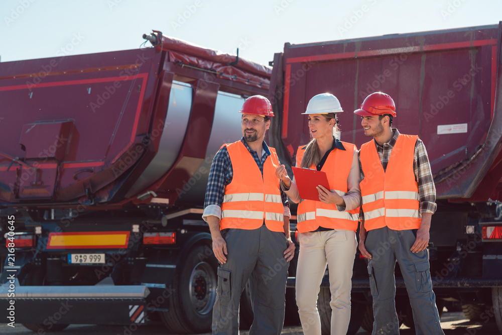 Fototapeta premium Truck drivers and dispatcher talking in front of lorries in freight forwarding company