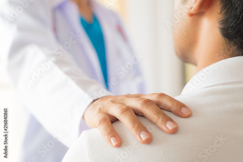 Female doctor put hand on patient shoulder for encouragement and discussion. Medicine and health care concept. Doctor and patient.