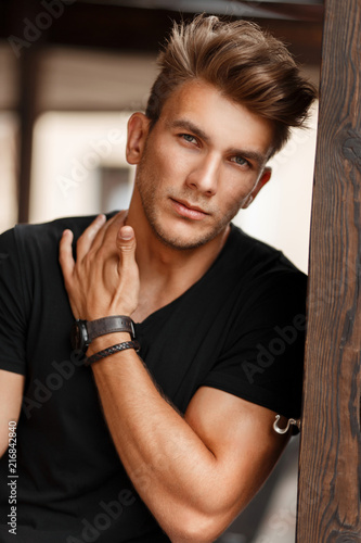 Obraz na plátně Fresh portrait of a beautiful young model man in a black T-shirt on a street nea