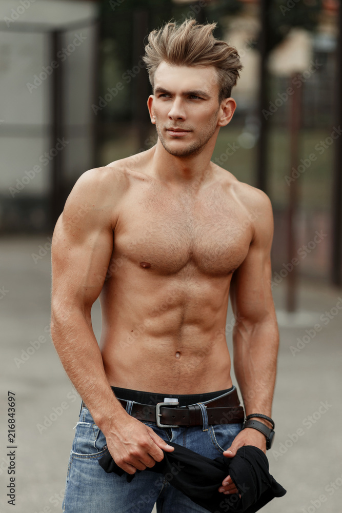 Fashionable handsome young man with healthy fitness body with muscles on  the street Stock Photo