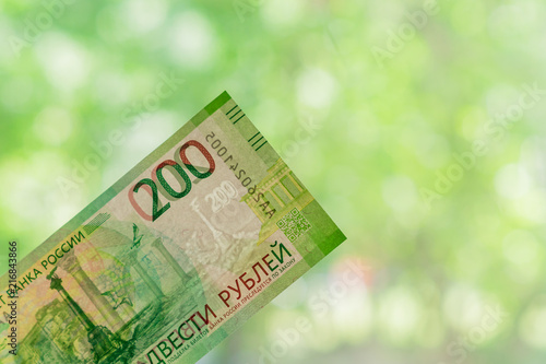 new russian banknote against green bokeh background. two hundred roubles. Cash paper money.