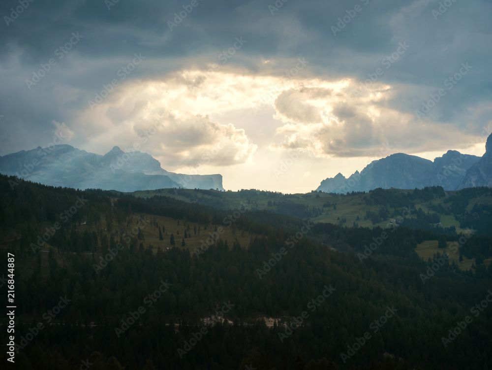 Fototapeta premium Sun beams and clouds at sunset over the mountains
