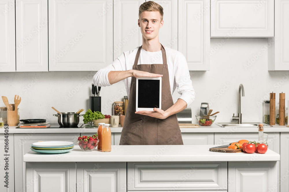 handsome young man holding tablet with blank screen in kitchen handsome young man holding tablet with blank screen in kitchen