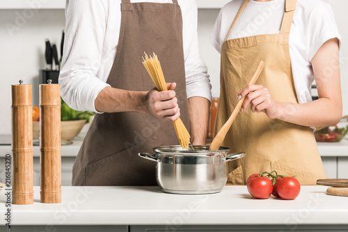cropped image of young couple cooking pasta in kitchen