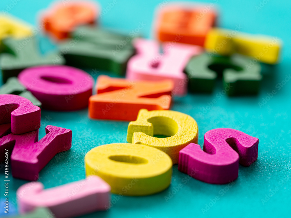 Naklejka premium closeup of colorful wooden alphabet on green background.