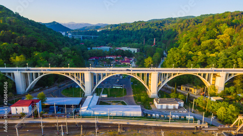 Drone view of the Matsesta viaduct and railroad on the background of mountainsides with dense forest in sunny summer day, Sochi, Russia
