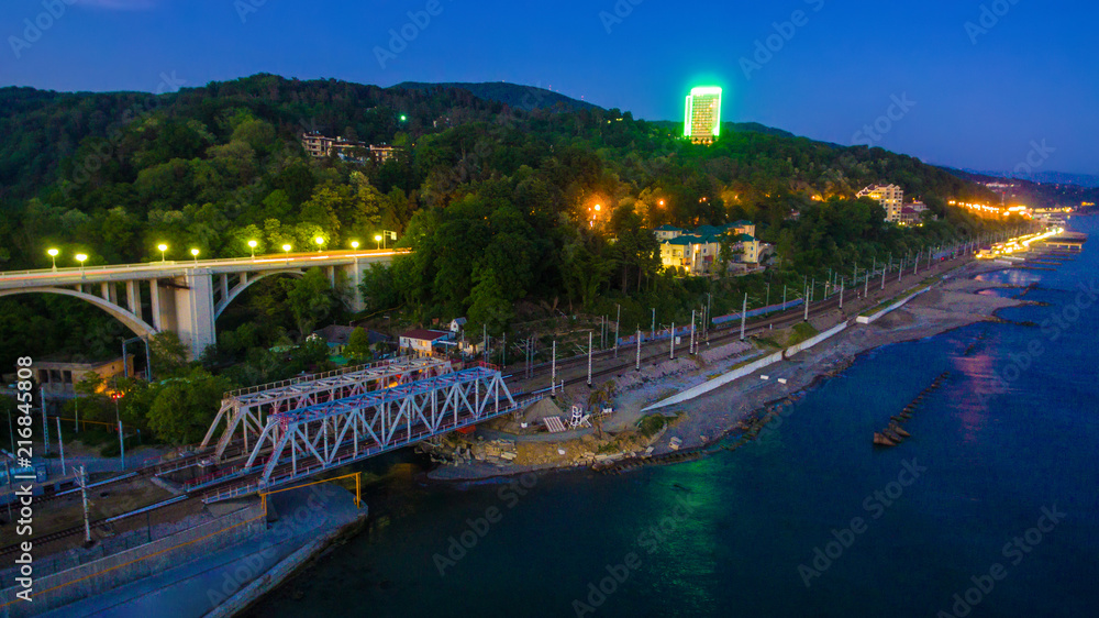 Drone view of the seaside with the Matsesta viaduct, the railway bridge and the mountain with dense forest at twilight, Sochi, Russia
