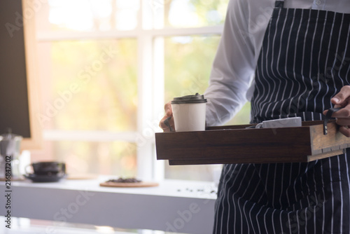 barista man holding cup of hot coffee to drink in cafeteria with copy space for text on advertisement board