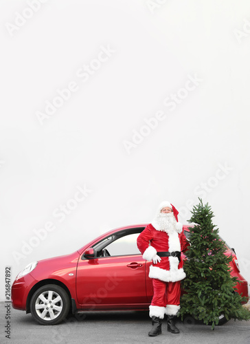 Authentic Santa Claus with Christmas tree near red car, outdoors