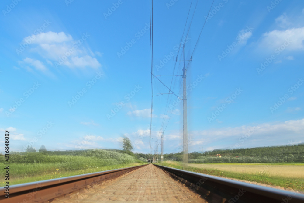 An electrified railway track among green meadows and wheat fields. Railway Transportation Infrastructure. Safety of the transport system. Ecology of technological breakthrough. Railway in Poland An electrified railway track among green meadows and wheat fields. Railway Transportation Infrastructure. Safety of the transport system. Ecology of technological breakthrough. Railway in Poland