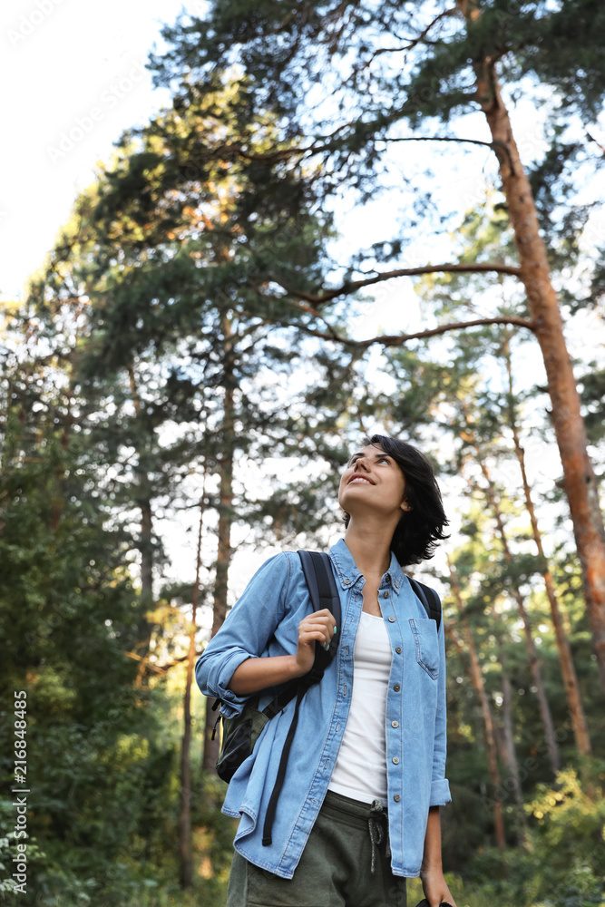 Young woman with backpack in forest on summer day. Camping season Young woman with backpack in forest on summer day. Camping season
