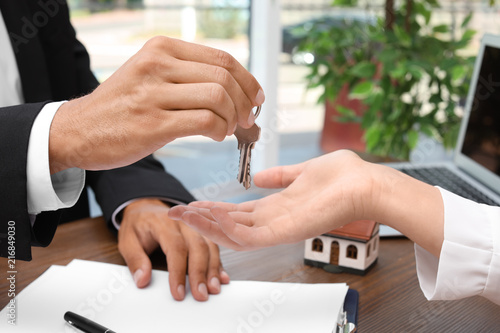 Real estate agent giving keys to woman at table